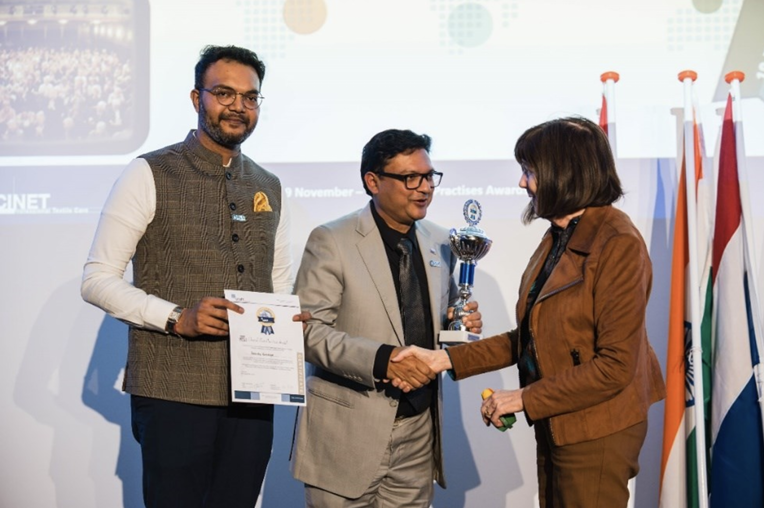 Mrs. Jan Barlow, Country Coordinator USA, congratulates Mr. Jash Dalal and Mr. Anup Poddar of The Laundry Concierge, India, with their Overall Award 2024, Category RTC-Sme.
